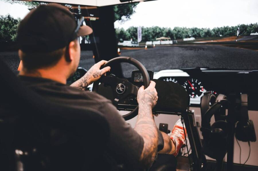 Focused gamer experiencing a detailed driving simulation setup indoors.