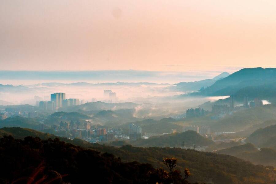 Captivating view of Taipei's skyline surrounded by misty hills during sunrise, showcasing nature and urban harmony.