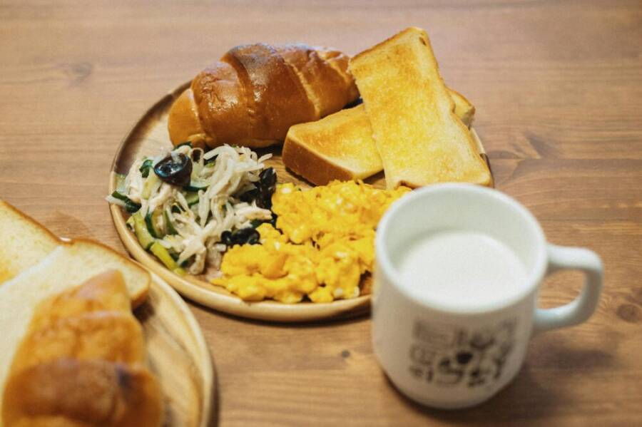Tasty Japanese breakfast with scrambled eggs, bread, salad, and milk. Captured in Itabashi City, Tokyo.