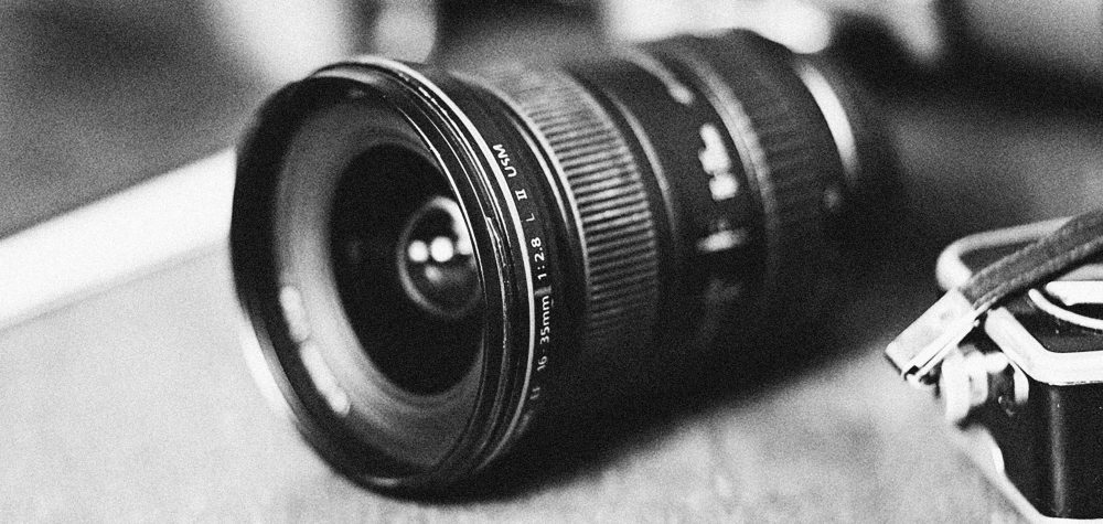 A monochrome close-up of a wide-angle camera lens with vintage appeal.