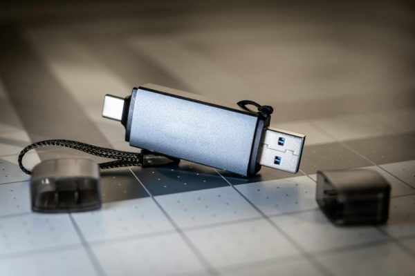 手機OTG無法讀取隨身碟:格式與供電問題快速解決 High-quality close-up of a dual USB-C and USB-A flash drive on a sleek grid-patterned background.