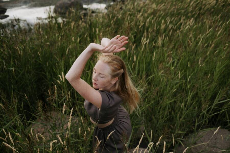 A young woman dances with grace surrounded by lush greenery, embodying peace and harmony with nature.
