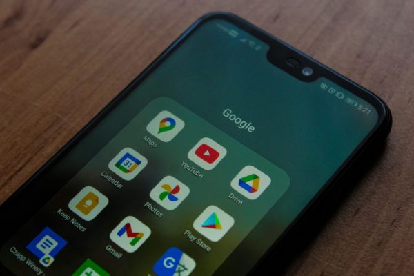 Google Play 無法下載或更新?快取清除與帳號修復步驟 Close-up of a smartphone showing various Google apps on its screen.