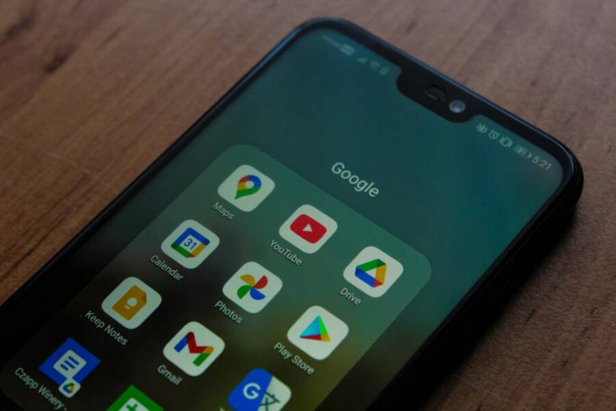 Close-up of a smartphone showing various Google apps on its screen.