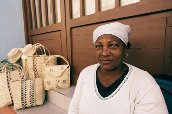 Woman with handmade bags displayed on a city street corner in an urban environment.
