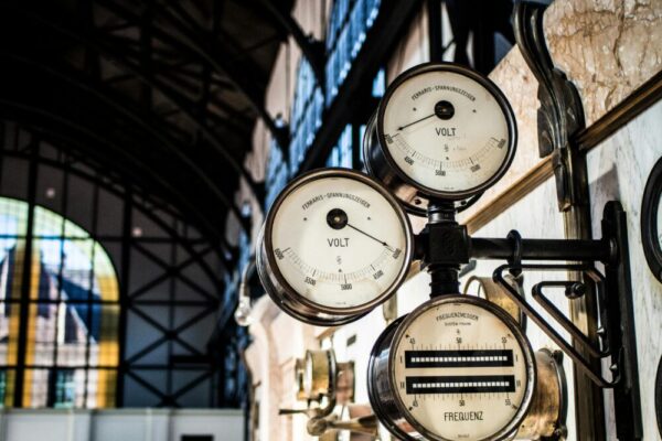 Intricate vintage volt and frequency gauges in an industrial setting with blurred background.