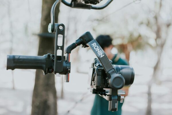 Close-up of a camera mounted on a Ronin stabilizer outdoors, capturing videography equipment in use.