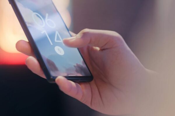Close-up of a hand holding a smartphone locked with a fingerprint sensor.