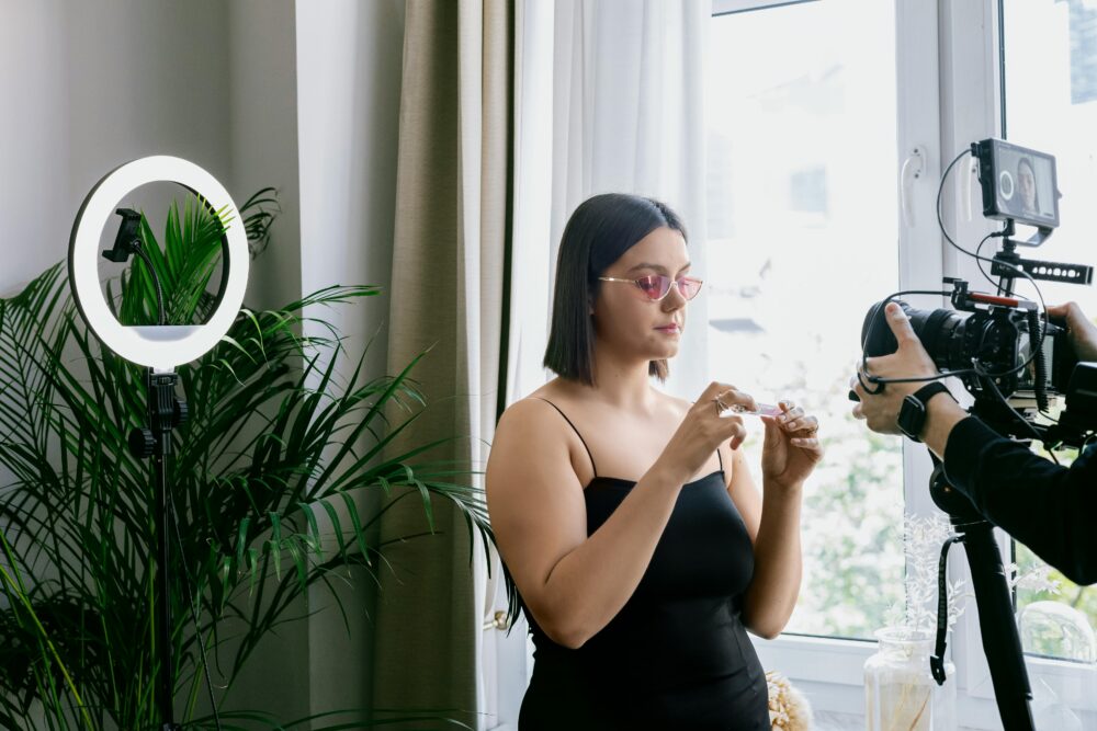 Woman filming a product review indoors with a camera and ring light