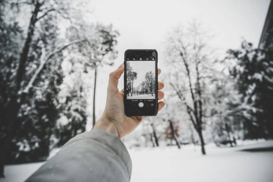 手持手機拍攝雪景的場景，象徵在拍照或切換功能時可能遇到卡住
