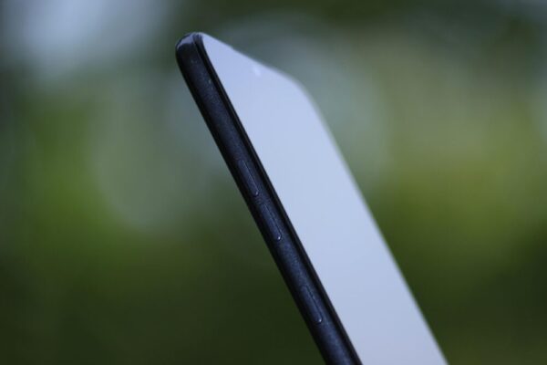 Side view of a sleek smartphone with a blurred green background, highlighting its slim design and buttons.
