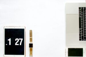 Modern minimalist flat lay featuring a laptop, smartphone, tablet, and smartwatch on a white background.