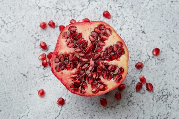 A detailed image of a pomegranate half with seeds on a marble background, showcasing vibrant red hues.