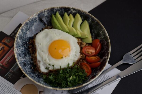 A delicious bowl featuring egg, avocado, tomatoes, and greens for a balanced meal.