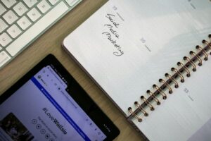 FB廣告組合包設計:一週三版本貼文素材全攻略 Top view of a notebook, tablet, and keyboard used for social media marketing planning.