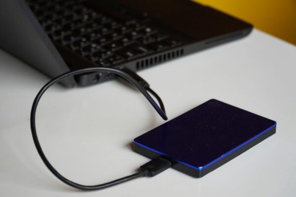 外接硬碟手機備份指南:exFAT 與 NTFS 相容性解析 External hard drive connected to a laptop, showcasing portable storage solution.