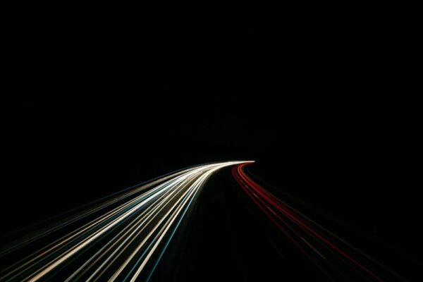 Dynamic long exposure capturing light trails on a dark highway at night.