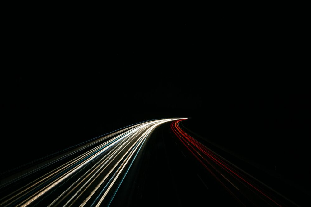 Dynamic long exposure capturing light trails on a dark highway at night.