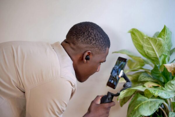 A man uses a phone gimbal for vlogging indoors, showcasing technology and creativity