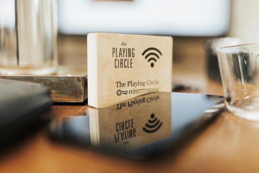 A wooden block displaying Wi-Fi details sits on a modern office desk.