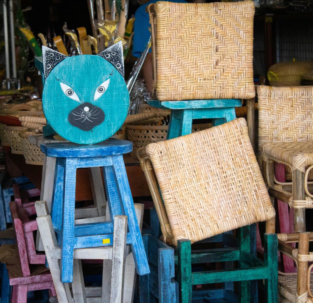 Vibrant wicker chairs and wooden stools display in Malacca market, Malaysia.