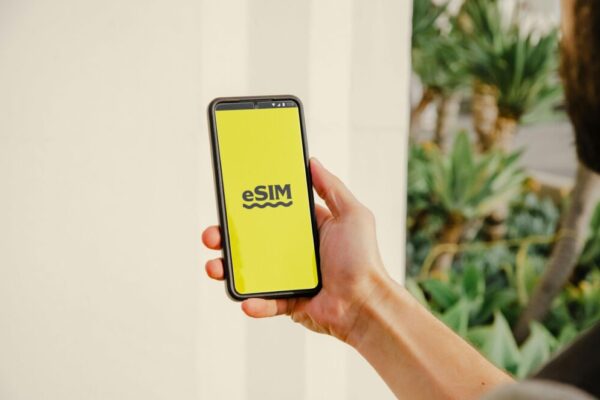 A person holds a smartphone with an eSIM logo outdoors, showcasing technology in Los Angeles.