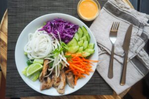 Vibrant Vietnamese noodle bowl with chicken, fresh vegetables, and spicy dressing.