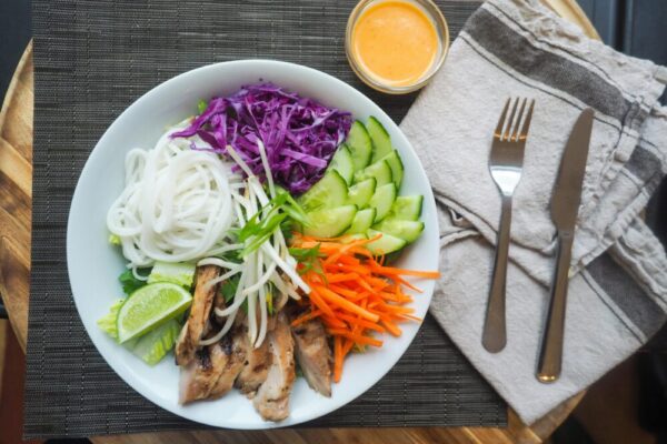 Vibrant Vietnamese noodle bowl with chicken, fresh vegetables, and spicy dressing.