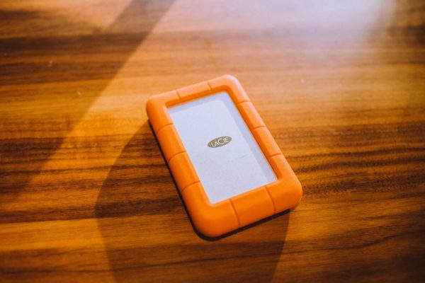手機影片長期備份:3-2-1規則實用指南 Close-up of an orange portable hard drive on a wooden table, perfect for tech and business themes.