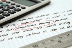 線上課程定價怎麼定?銷售心理學實用技巧 Focused image of handwritten business notes with calculator emphasizing pricing strategy.