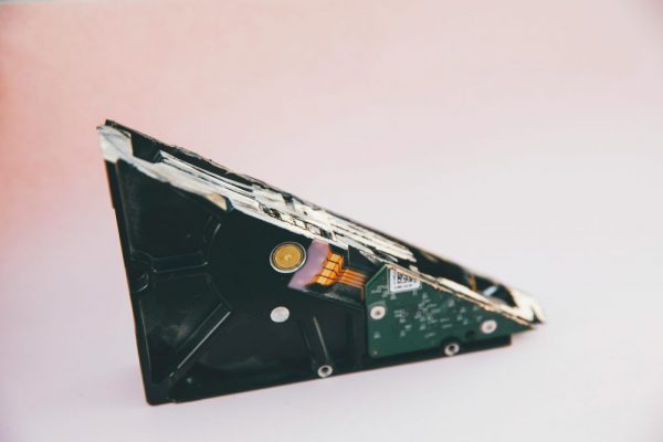 APP 資料搬家常見坑位整理:手機遷移避雷全指南 Close-up of a broken hard disk drive showing internal components on a pink background