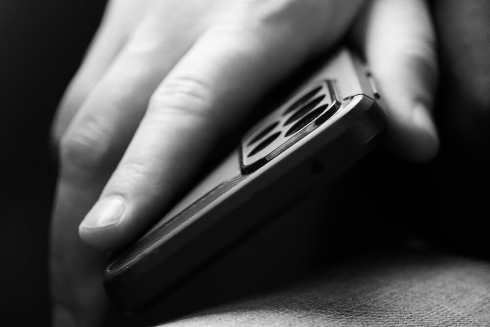 Black and white closeup of a hand holding a smartphone, showcasing modern mobile technology
