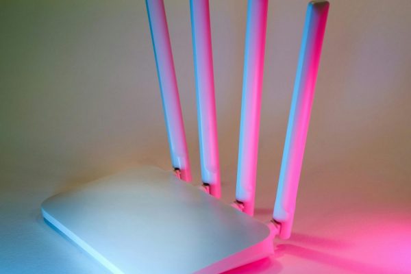 手機連智慧家電不穩怎麼辦?2.4GHz與5GHz分流配對實用教學 A sleek wireless router enhanced by vibrant neon lights, showcasing cutting-edge technology.