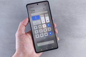 Close-up of a hand holding a smartphone with settings panel visible, focus on screen.