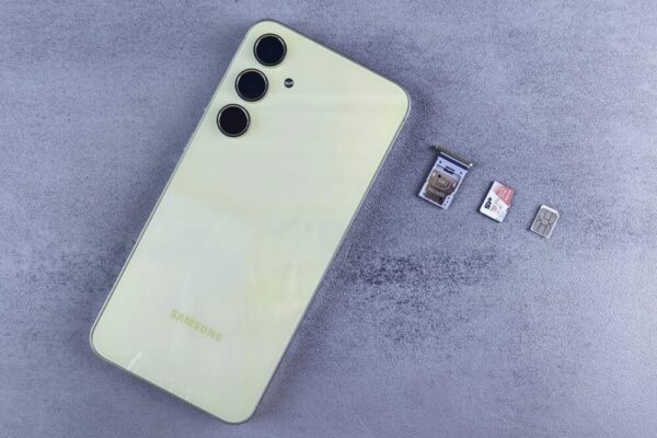 Yellow smartphone with SIM tray, memory card, and SIM card on gray background
