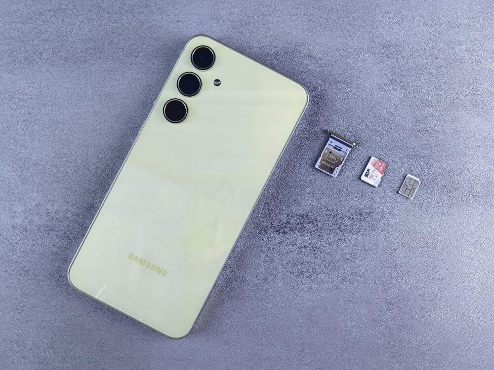 Yellow smartphone with SIM tray, memory card, and SIM card on gray background