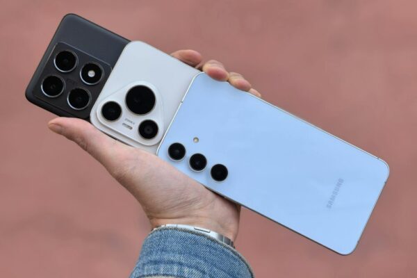 Zenfone 11 與 iPhone 16 對比:單手操作與攝像頭影像表現全面解析 A hand holding three smartphones showcasing various camera designs