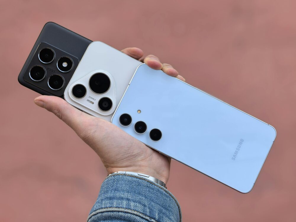 A hand holding three smartphones showcasing various camera designs