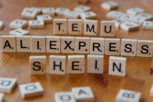 Wooden Scrabble tiles display popular e-commerce platforms on a wooden surface.