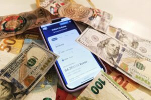 自架官網 vs 電商平台:利弊分析與選擇指南 A smartphone displaying a currency converter surrounded by dollar and euro banknotes, highlighting exchange rates.