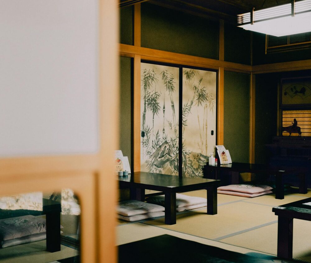 Serene view of a traditional Japanese tatami room with painted sliding doors and low tables.