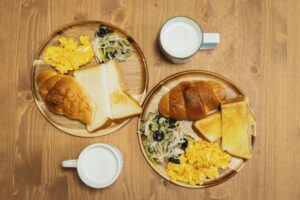 Delicious Japanese breakfast featuring eggs, toast, and milk on a wooden table setting.