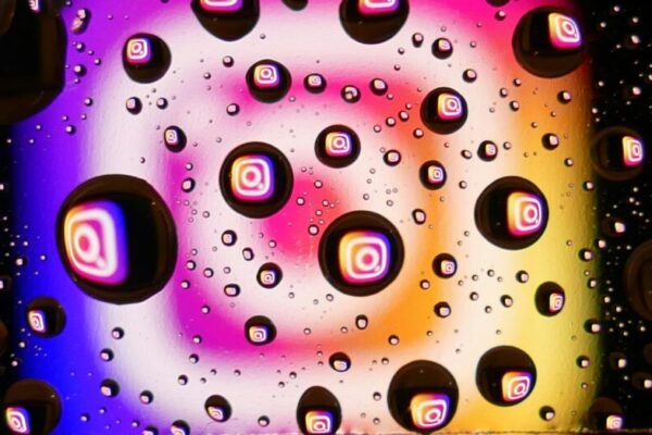 不露臉行銷跨平台分發策略:抖音小紅書IG Reels YouTube Shorts發佈節奏 Vibrant water droplets on a colorful background reflecting Instagram logos, showcasing abstract digital creativity.