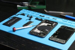Close-up of disassembled smartphone parts on a blue repair mat with tools