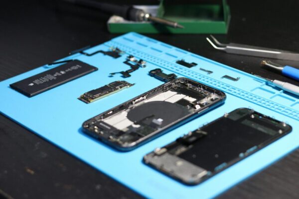 Pixel 9 與 Galaxy S24 演算法與硬體協同:相機、處理器與顯示的實用比較 (Pixel 9 与 Galaxy S24 演算法与硬件协同) Disassembled smartphone with tools on a workbench, emphasizing repair and technology