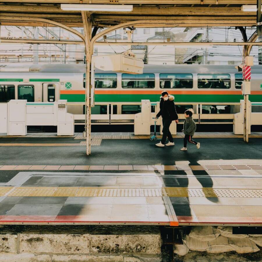 A father and son walk along the platform at a Tokyo train station during the early evening.