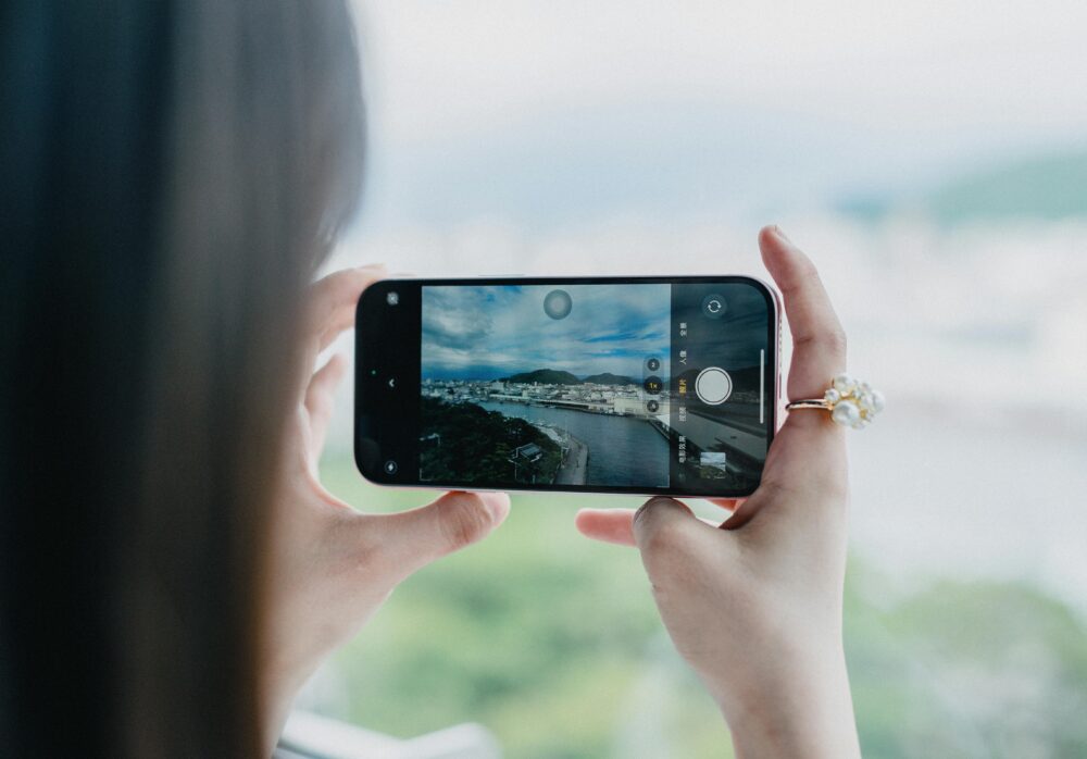 A person photographing the beautiful coastline of Nishiizu, Shizuoka, Japan, emphasizing travel and exploration.