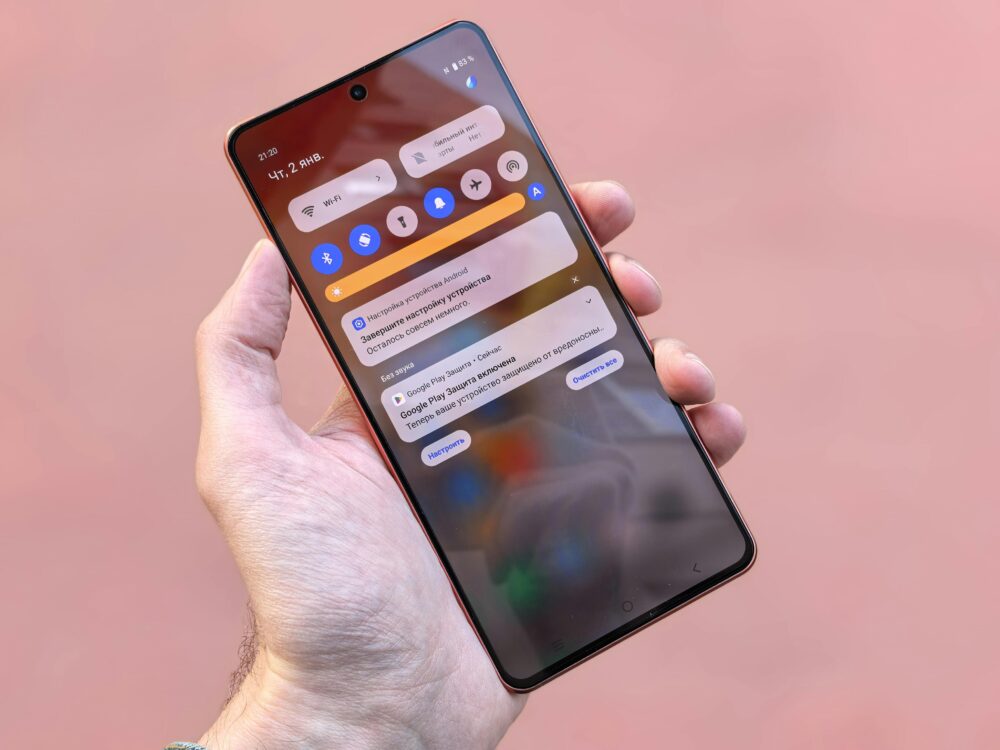 Close-up view of a person holding a smartphone showing notifications and icons on screen