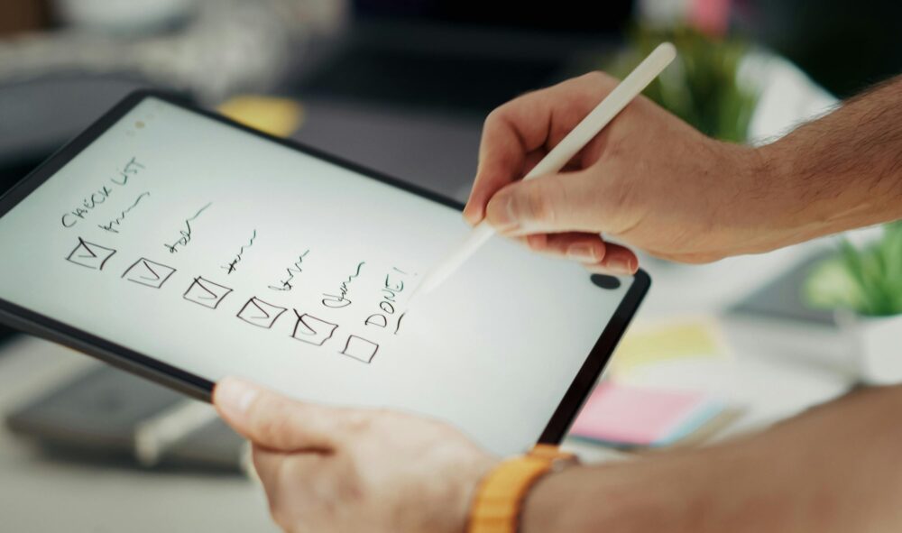 Close-up of a hand writing on a digital checklist using a stylus on a tablet