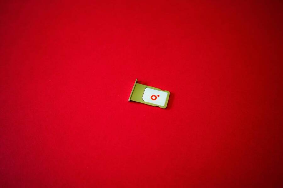 A clean image of a SIM card tray displayed on a vibrant red background.